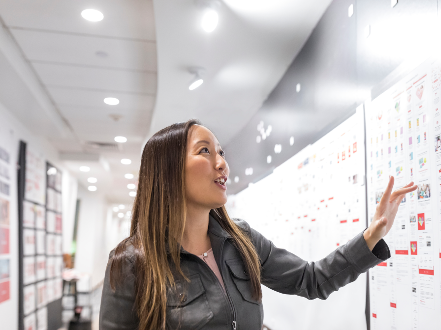 A woman looking at a board on the wall with different information and graphics.