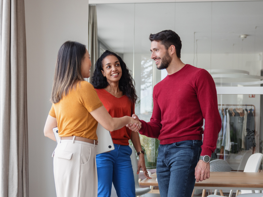 Three colleagues shaking hands and smiling