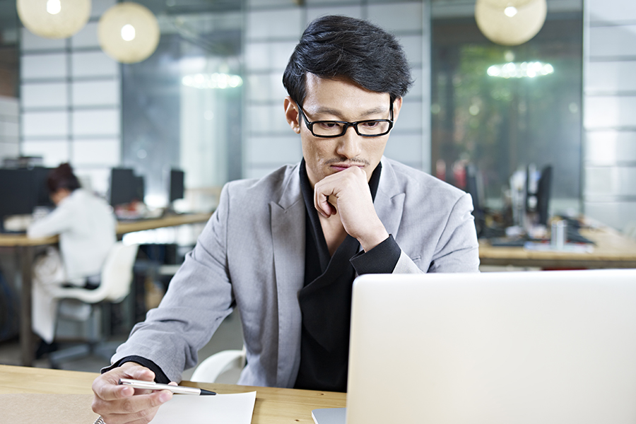 Man wearing glasses looking at laptop